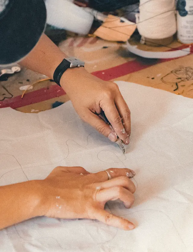 Tangan menggambar garis tipis di atas pola kertas.